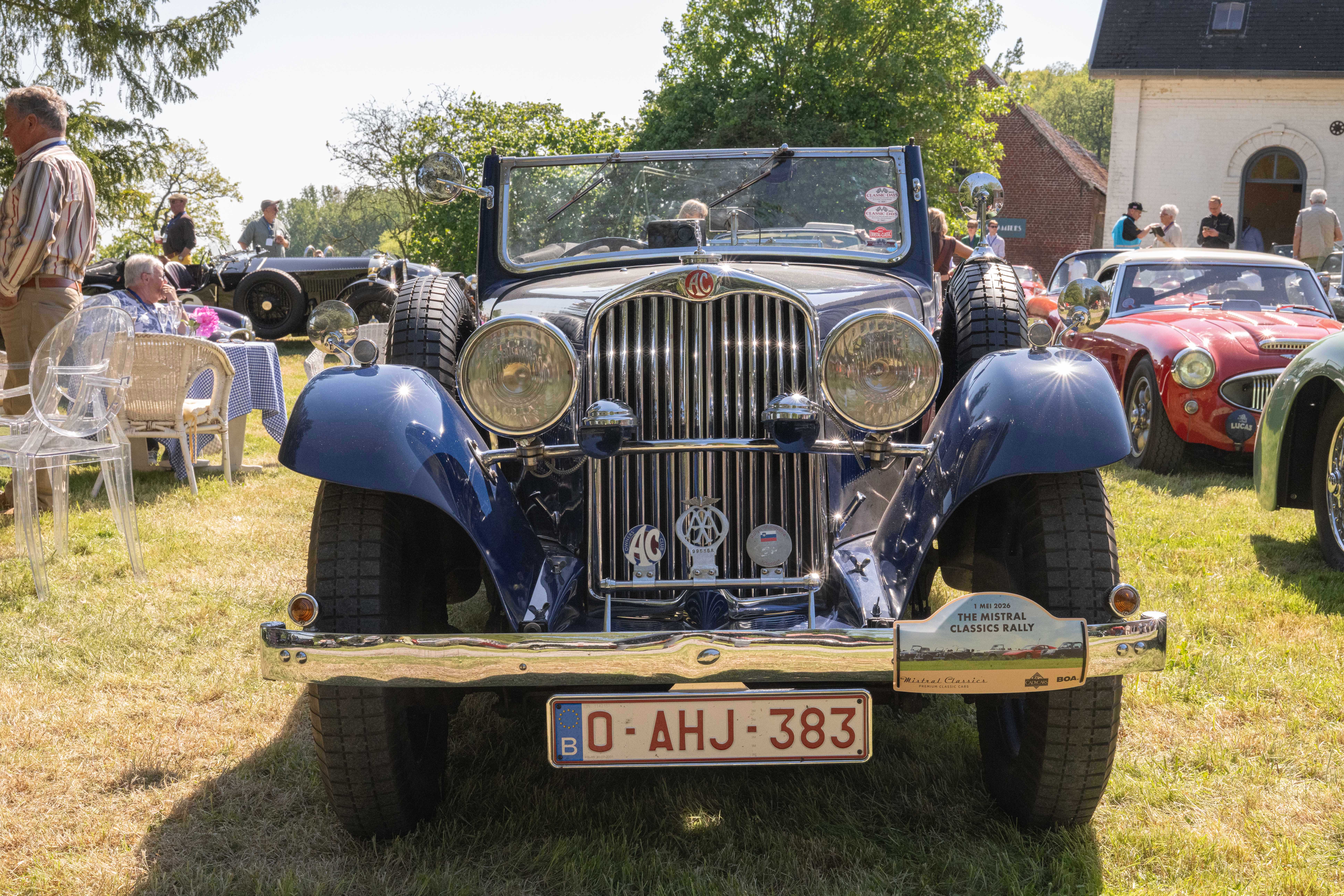 Jeep décapotable bleue vintage avec phares ronds et calandre chromée lors d'une exposition automobile.