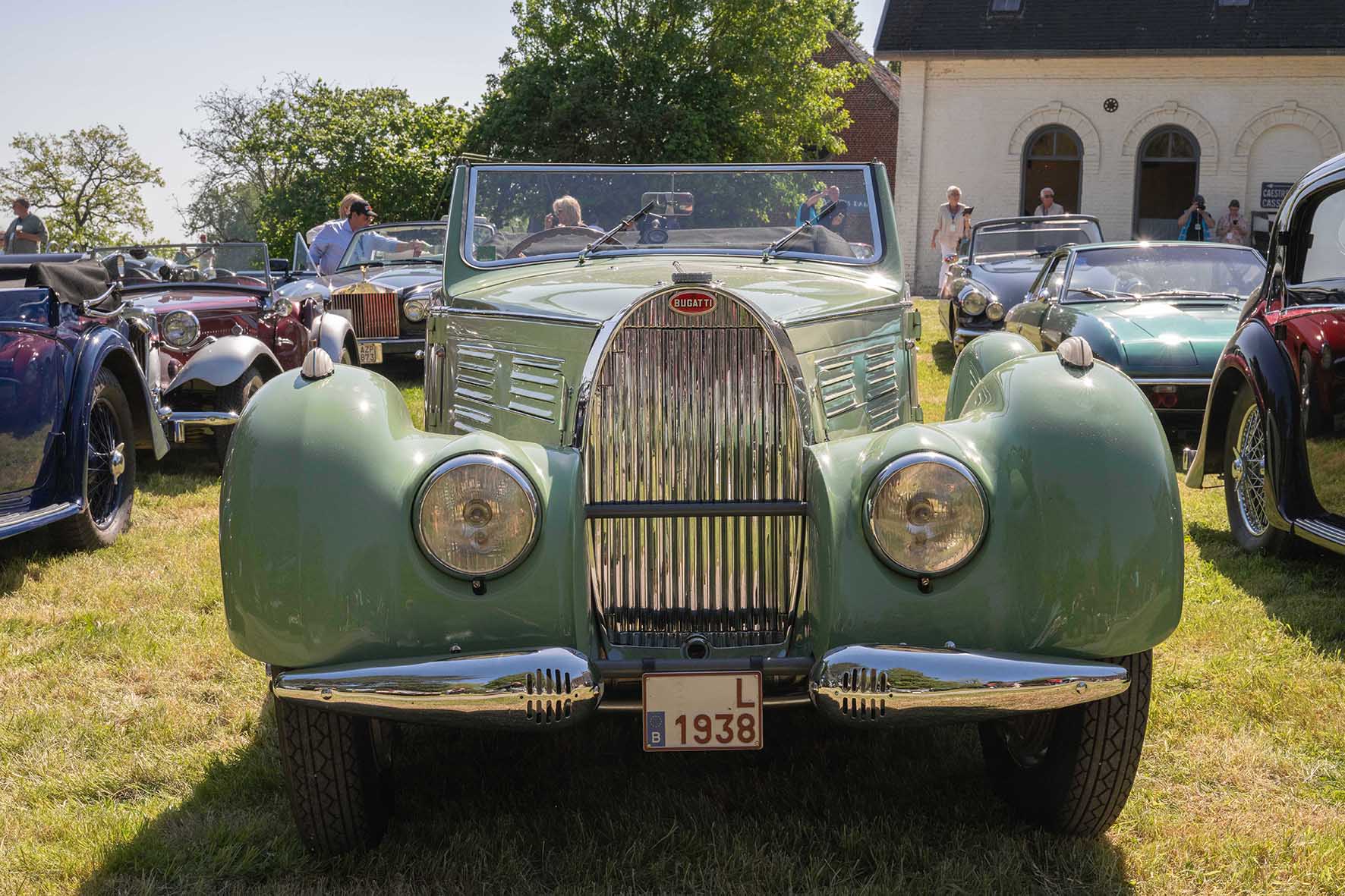 Élégante automobile Bugatti Type 57 de 1938 en vert amande exposée lors d'une réunion de voitures anciennes, vue de face avec ses phares emblématiques.